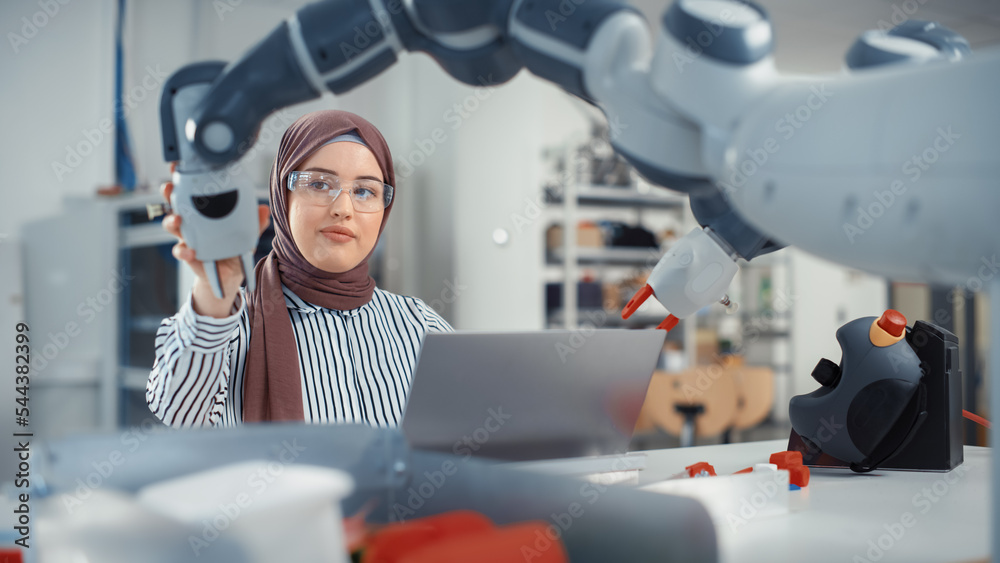 Aufkleber Modern Office: Portrait of Muslim Businesswoman Wearing Hijab and Working on Engineering Project, Coding on Laptop and Changing Robot Hand Position. Empowered Engineer With Startup Project.