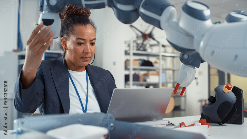 Poster Portrait of Black Female Senior Engineer Working on Engineering Project, Coding on Laptop and Changing Robotic Hand Position in Modern Office. Empowered Scientist with Creative Project.