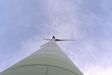 Low angle view on propeller and column of on-shore wind turbine against blue sky supplying with renewable energy the needs of inhabitants. It is example of alternative energy resources.