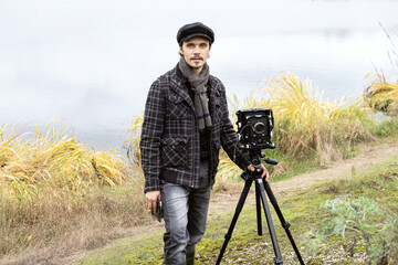 Portrait of photographer with wide angle retro camera. Looking at the camera. Shooting an autumn landscape with an old camera. Concept - old classic process, film camera, retro. Selective focus.