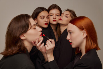 Portrait of young beautiful women in black jackets and red lipstick makeup posing over grey background. Party look
