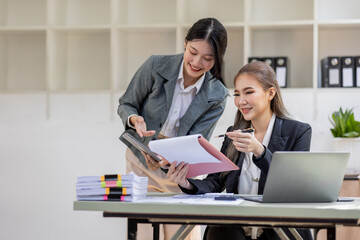 Two young asia business woman working together in office space, doing planning analyzing the financial report, business plan investment, finance analysis concept.