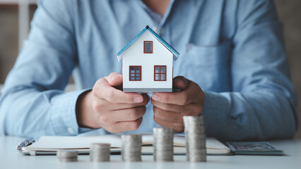 People with house models and piles of coins are calculating and recording income and expenses for financial planning, financial planning ideas for home and real estate purchases.