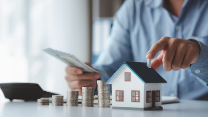 People with house models and piles of coins are calculating and recording income and expenses for financial planning, financial planning ideas for home and real estate purchases.