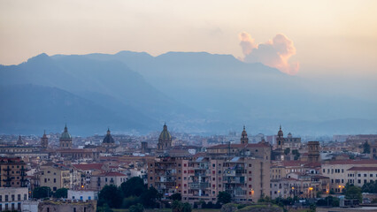 Residential Homes and Historic Church Buildings with mountains in background in Palermo, Sicily, Italy. Sunny Sunset Sky.