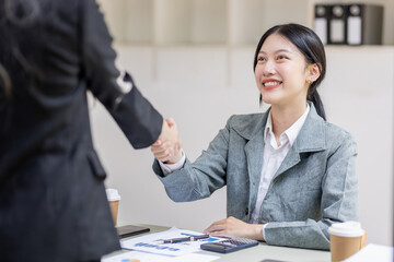 Two young asia business woman shaking hands successful making a deal, business woman  handshake. Business partnership meeting handshake concept.