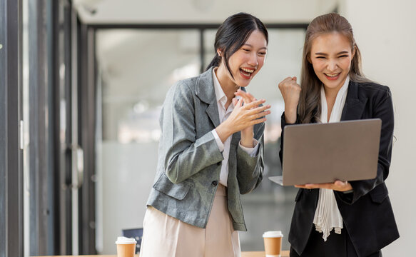Pretty Two Asian businesswoman sitting on a tablet  laptop And the work came out successfully and the goal was achieved, excited winners or happy people and satisfied with her.