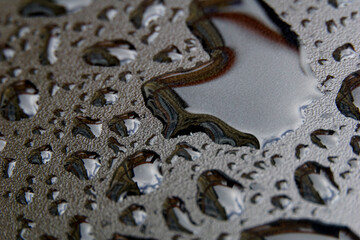 water drops on a gray plastic surface, horizontal, with narrow depth of field.