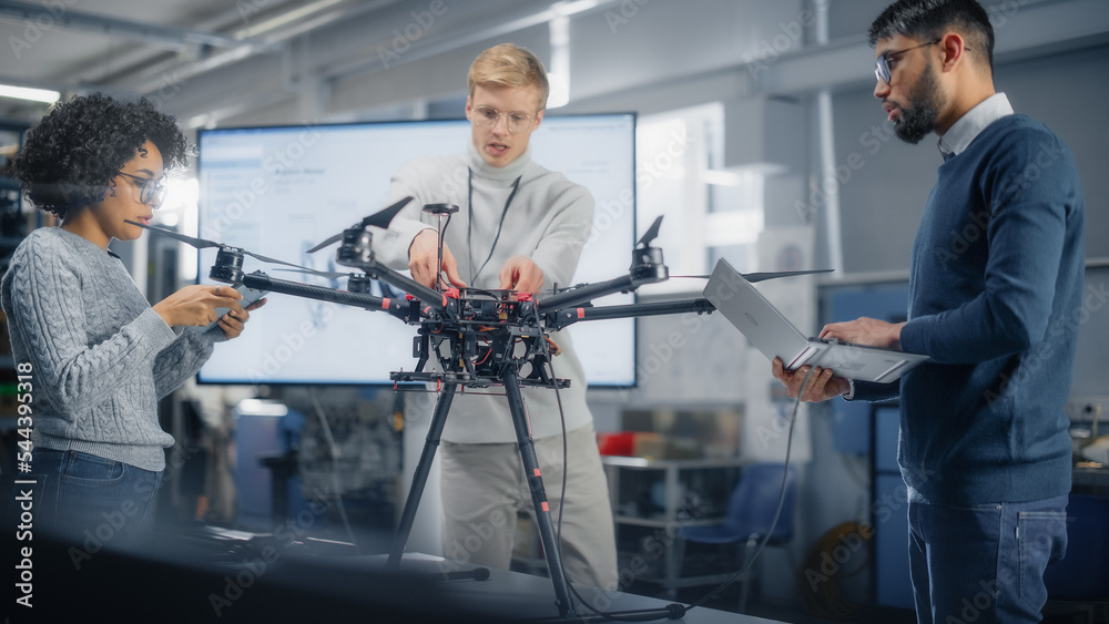 Aufkleber Black Male Engineer Coding on Laptop While Programming Drone with his Colleagues In the Factory Laboratory. Scientific Research, Design, Operation and Performance of Machine Mechanism Concept.