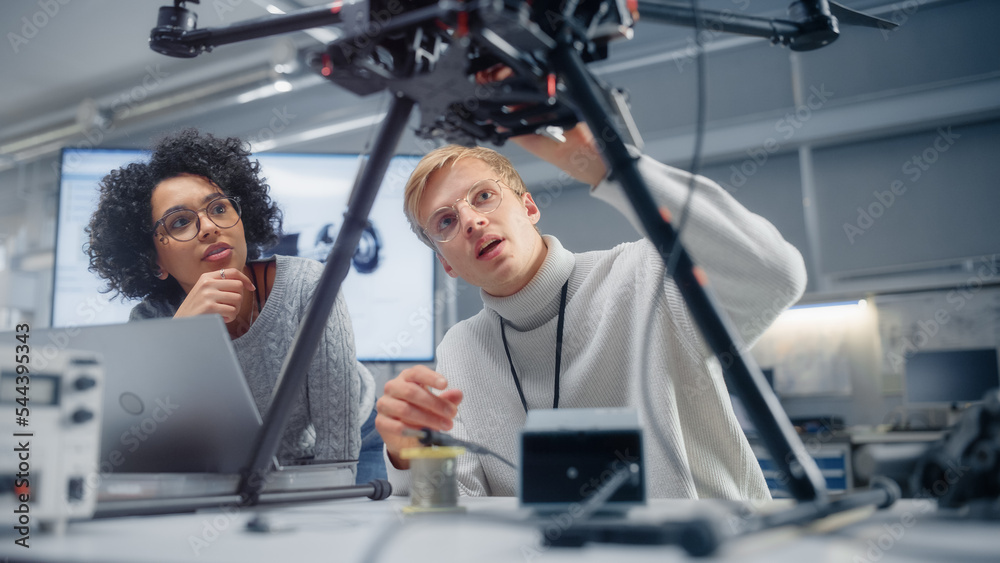 Aufkleber Male Engineer Puts Processor in the Drone While Female Developer Programming on Laptop Computer. Futuristic and Innovative Technologies for Unmanned Aerial Vehicle Concept.
