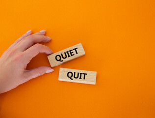 Quiet quit symbol. Concept word Quiet quit on wooden blocks. Businessman hand. Beautiful orange background. Business and Quiet quit concept. Copy space