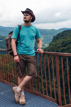 Male traveler in Okatse Canyon in Georgia, walking on hanging metal pedestrian pathway trail above deep precipice, Summer day time. Vertical photo