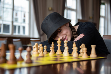 The girl plays chess. Pieces on the chessboard. Chess game, close-up, portrait. Chess tournament,...
