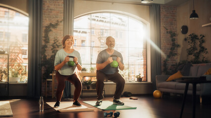 Happy Senior Couple Doing Morning Exercises and Kettlebell Workout Together at Home in Sunny Living Room. Concept of Healthy Lifestyle, Fitness, Recreation, Couple Goals, Wellbeing and Retirement.