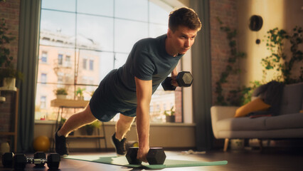 Fit Athletic Strong Young Man Performing Enduring Training in Plank Position, while Lifting...