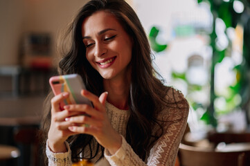 Portrait of beautiful young woman using smartphone in cafeteria