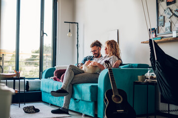 Couple petting their adopted dog while sitting on the couch at home