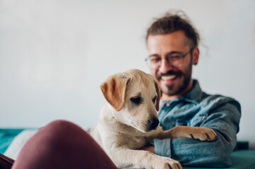 Man petting his adopted dog while sitting on the couch at home