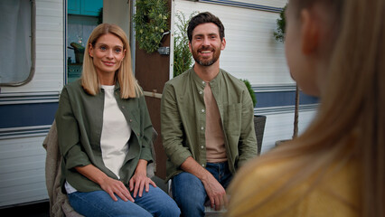 Back view unrecognizable child girl kid daughter tell poem singing song talk speak talking telling speaking to proud parents Caucasian mother and father sitting near of van trailer hugging listening