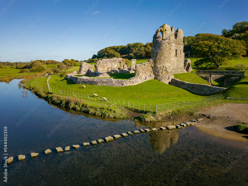 Wall mural Aerial view of stepping stones over a small river leading to the ruins of an ancient castle (Ogmore Castle, Wales) - Wall murals