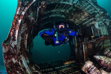 Scuba Diver on a closed circuit rebreather swimming through the wreckage of an old aircraft underwater