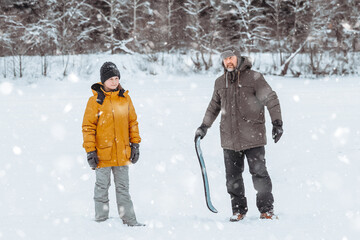 Fototapeta na wymiar Dad teaches his daughter to ride a snow skate in a winter park, family walk in the fresh air