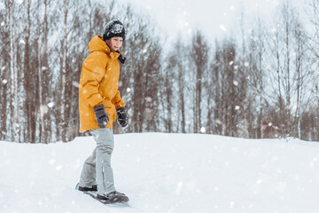 Fototapeta na wymiar Cute teenage girl rides a snowskate in a winter park, healthy lifestyle