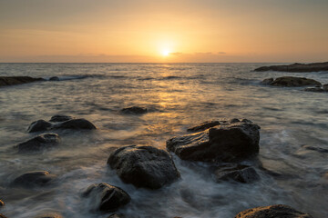 Rocky shore of the Atlantic Ocean at high tide at sunset