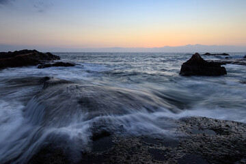 Rocky shore of the Atlantic Ocean at high tide at sunset