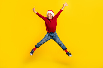Fototapeta na wymiar Full length photo of cute little boy jump high spread legs excited wait new year wear trendy red outfit isolated on yellow color background