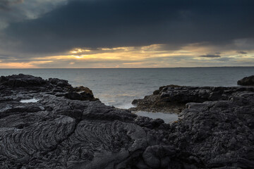 Solidified lava on the coast of the Atlantic Ocean at high tide at night