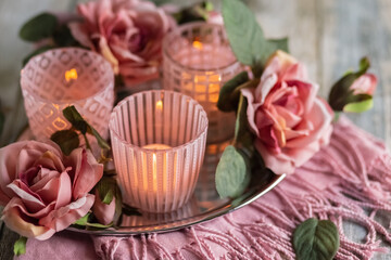 Pink glass candlesticks with candles and roses on a wooden table. Close up. Card. Photo