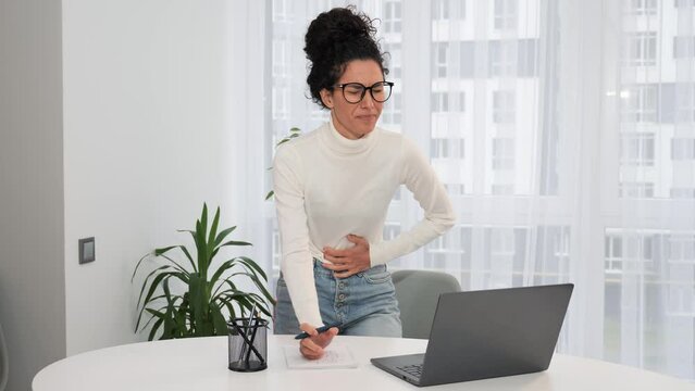 Young woman freelance working on laptop at home feels sudden menstrual abdomen pain gastritis discomfort diarrhea liver problems appendicitis symptoms indigestion stomach spasm ache indoor. 