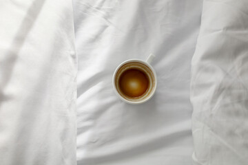Drunk cup of coffee in bed with white cotton bedclothes. Morning coffee concept. Sunday loneliness...
