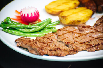 Delicious traditional barbecue dish. Grilled beef steak. Vegetables, string beans and potatoes. Healthy balanced meal. Traditional nicaraguan food.