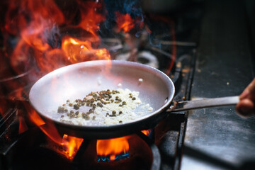 Burning pan. Cooking a special dish over high heat. Chef working. Real kitchen. Kitchen on fire.