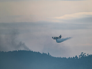 Fototapeta na wymiar Fire extinguishing plane water bomber dumping its load, Spain.
