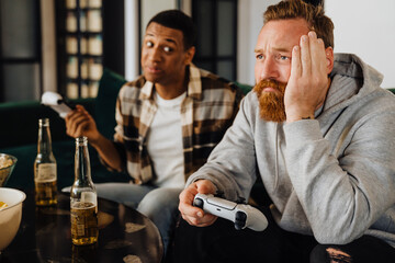 Upset white man playing video game with his friend and losing
