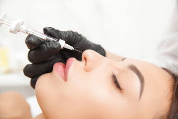 A cosmetologist gives a nose injection to fix the hump of a beautiful woman in a beauty salon. beauty injection.