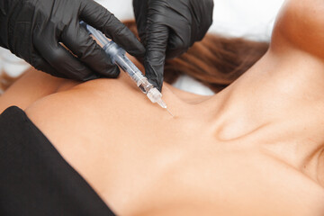 The cosmetologist makes anti-aging injections against wrinkles on the neck and in the decollete...