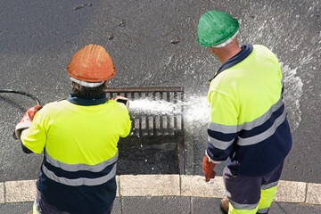 sewer workers working  for cleaning with water pressure on maintenance by the system sewage in city street - obrazy, fototapety, plakaty