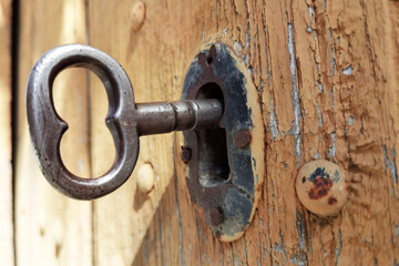 old metal key  in vintage lock on the wooden brown door