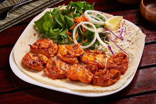 Spicy Sheesh Tawook or shish tikka boti kebab with salad, lemon and bread served in dish isolated on table side view of middle east food
