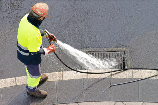 sewer workers working  for cleaning with water pressure on maintenance by the system sewage in city street