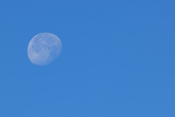 Luminous Moon during the day against the blue sky with copy space.