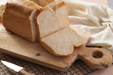 One freshly baked loaf of white wheat bread and cut slices on wooden board