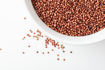 Red quinoa seeds in a white bowl.