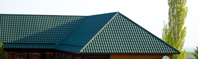 Roofs of houses from a metal profile against the sky. Roofing. Metal tiles on the roofs of houses.