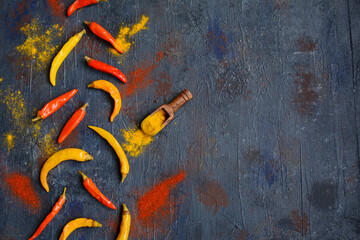 A layout of red and yellow hot chili peppers on a dark blue background. Top view, copy space