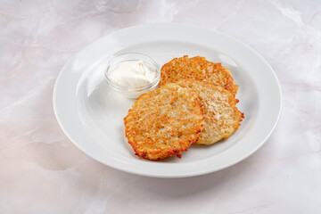 Potato pancakes fried in a frying pan and laid out on a white plate. Classic hash browns from potatoes